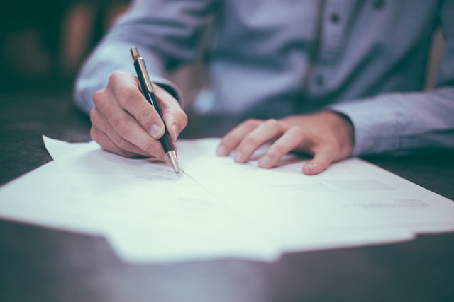 hands of a man signing papers on a desk